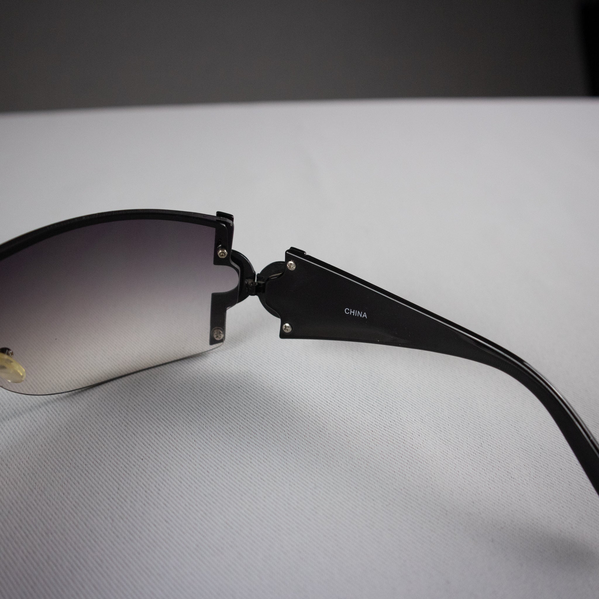 Black sunglasses with gradient lenses on a light gray surface