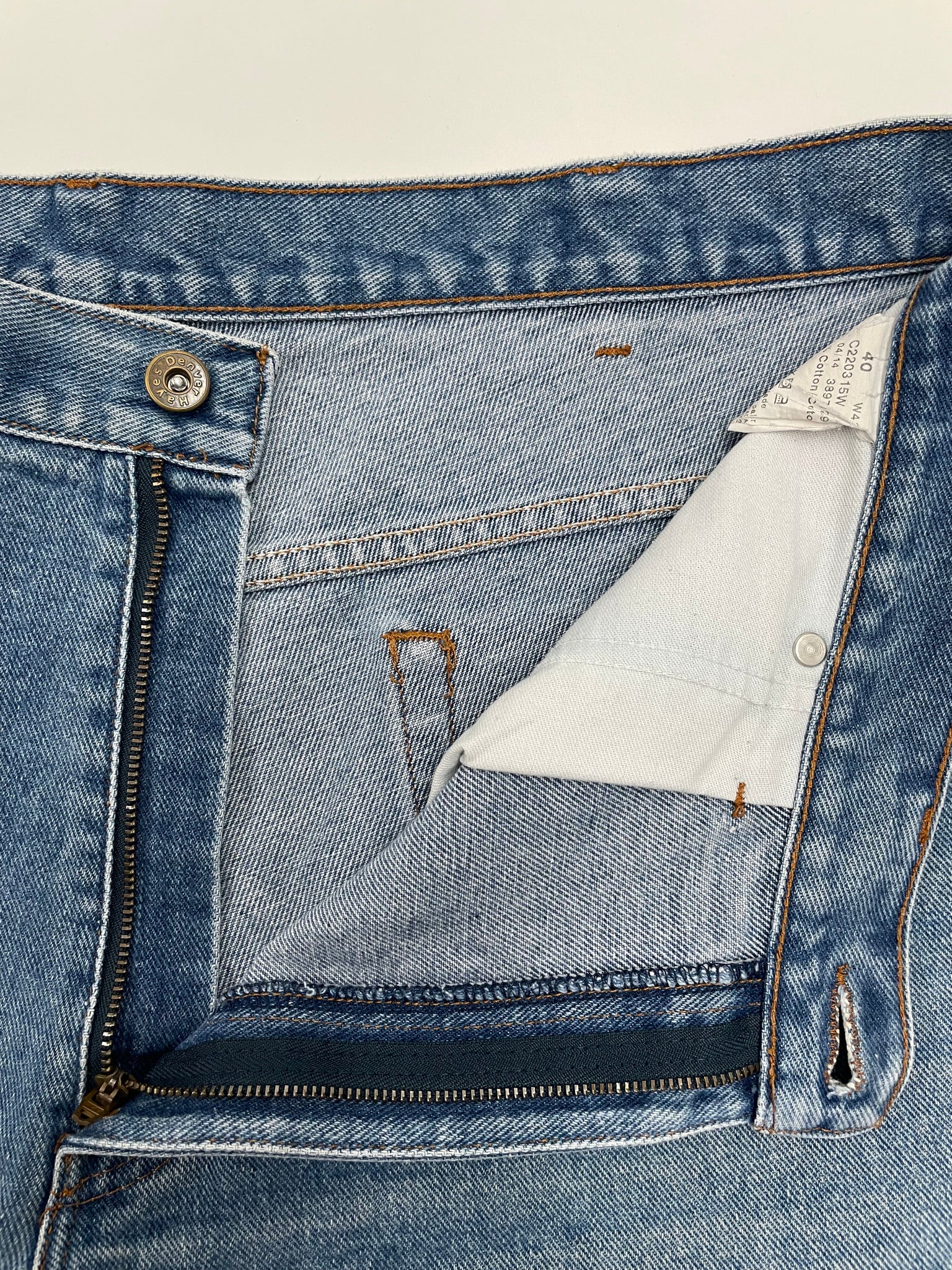 Close-up of a blue denim jacket with a zipper and button details on a beige background