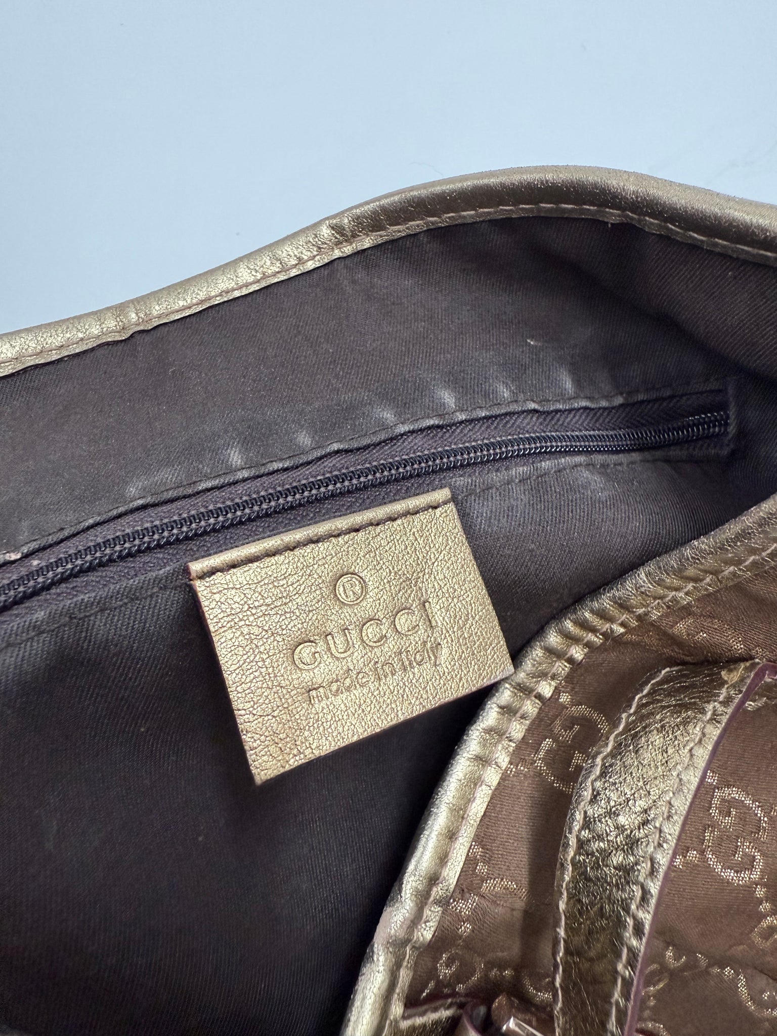 Brown patterned bag on a white background gucci hang bag gold design with iconic pattern high end designer luxury close up detail shot of made in italy tag 