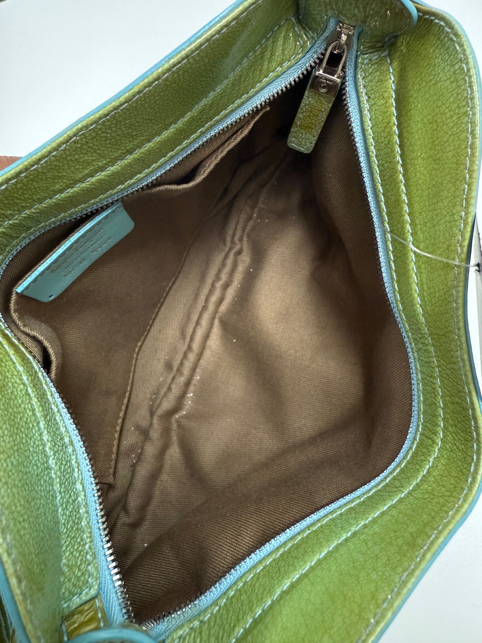 Green leather bag with a zipper, showing the interior.