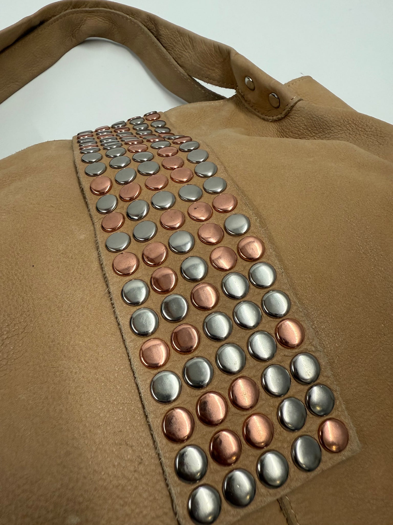 Brown leather bag with metal studs on a light gray background