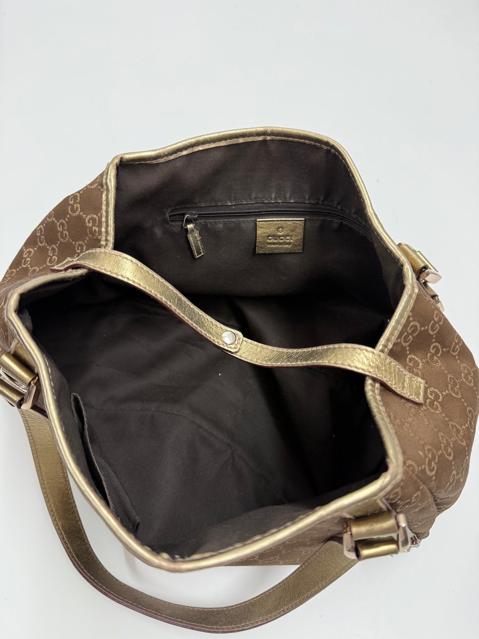 Brown patterned bag on a white background gucci hang bag gold design with iconic pattern high end designer luxury inner lining detail shot