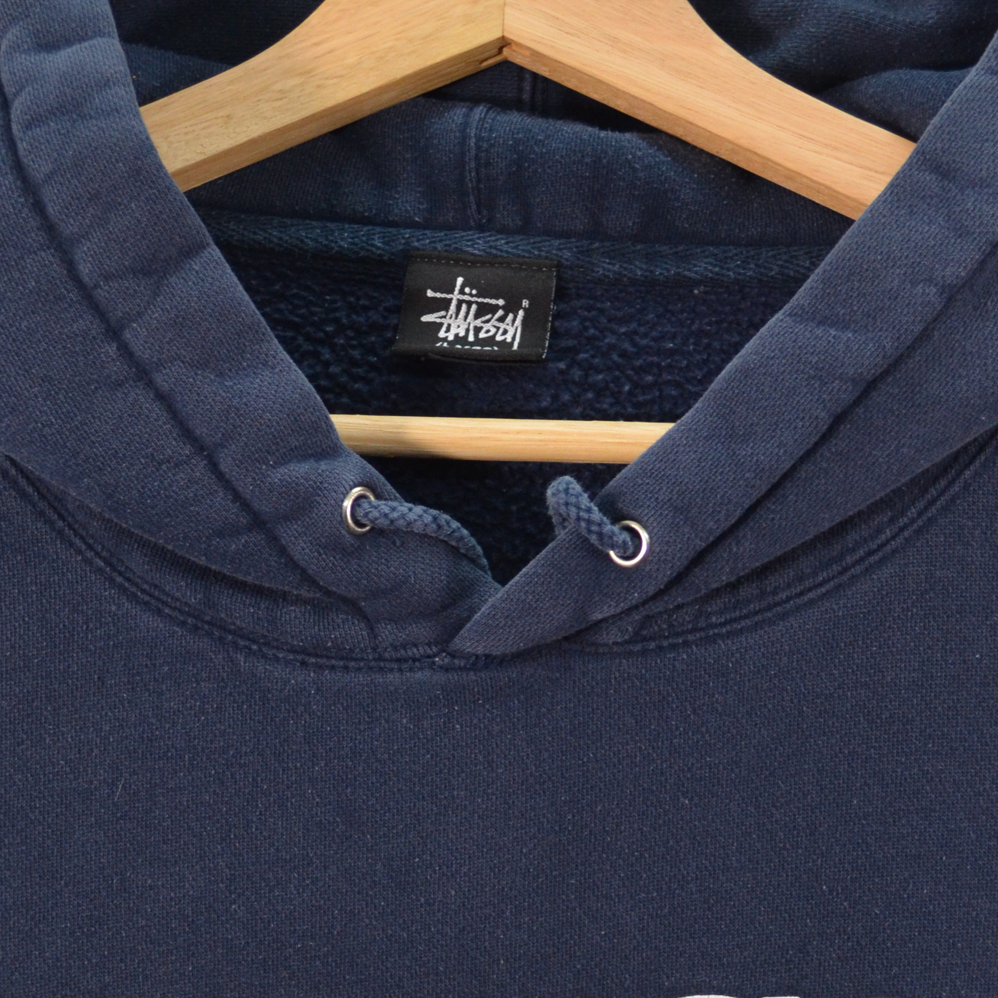 Navy blue hoodie with a brand label on a wooden hanger